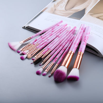 Set of makeup brushes with pink handles and rose gold accents on a light gray surface.