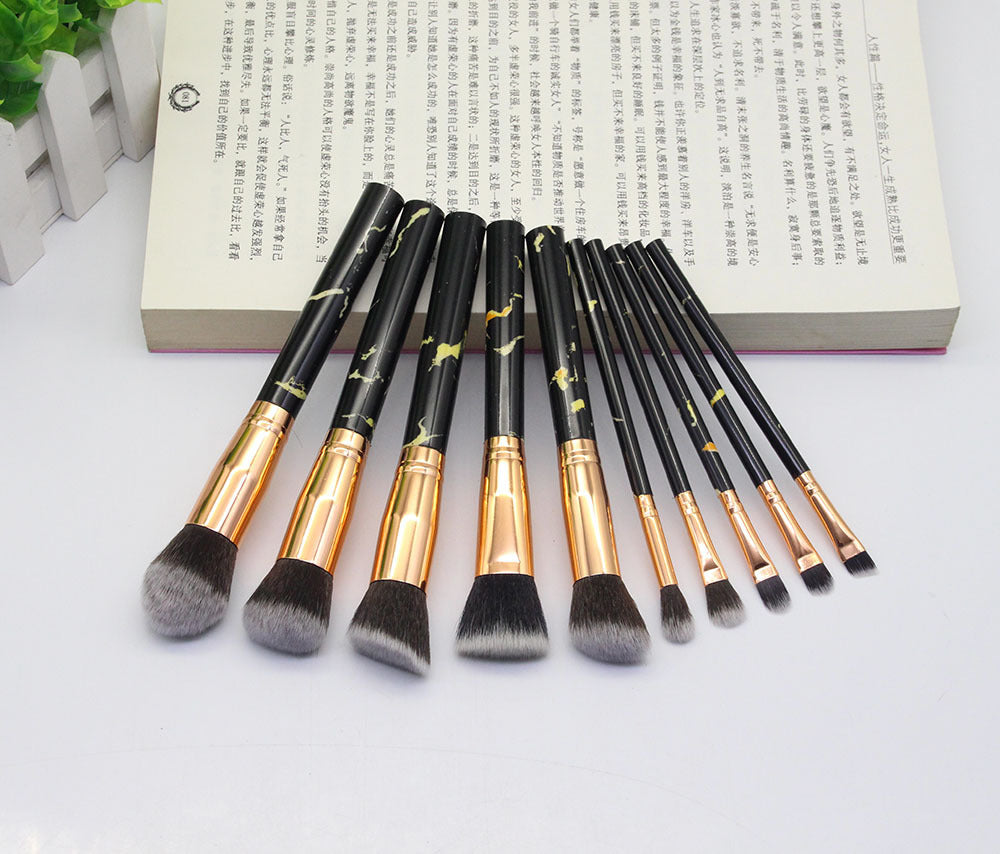Set of makeup brushes with black and gold handles on a white background