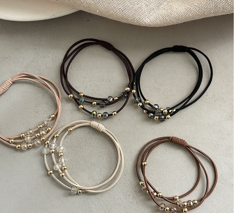 Five Durable Hair Rope Adult Hair Elastic Bands in neutral tones laid out on a flat surface, featuring gold and crystal bead accents.