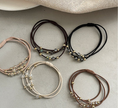 Five Durable Hair Rope Adult Hair Elastic Bands in neutral tones laid out on a flat surface, featuring gold and crystal bead accents.