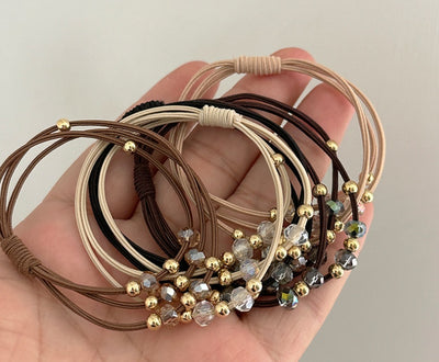 Close-up of Durable Hair Rope Adult Hair Elastic Bands in various colors with gold and crystal beads, held in a hand for detail view.