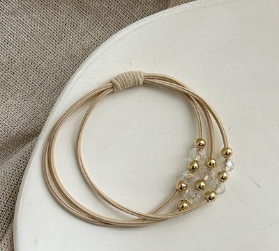 Single beige Durable Hair Rope Adult Hair Elastic Band with gold and clear crystal beads, displayed on a white surface.
